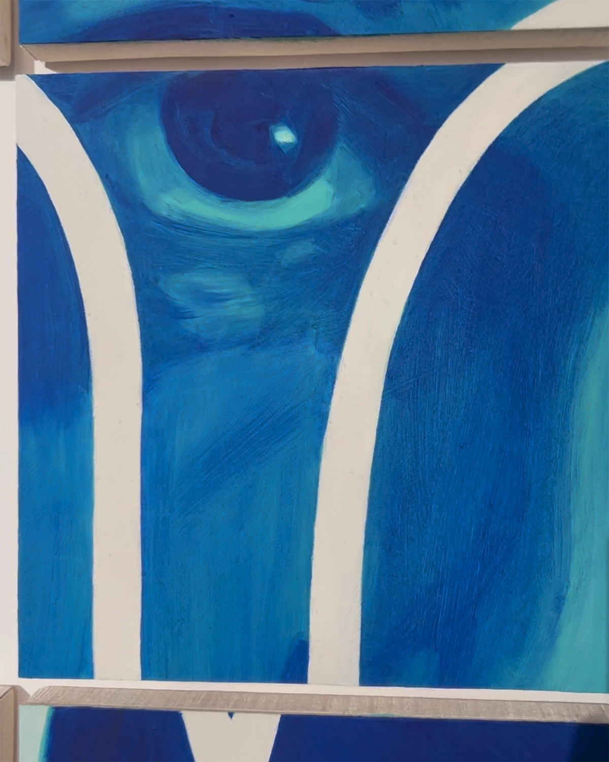 A close-up of a blue and green artwork on a white wall.